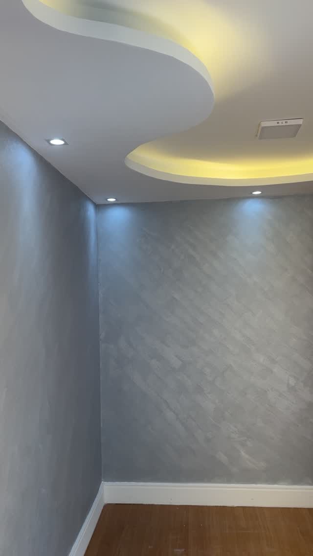Ambiente residencial com teto curvo, luz indireta e parede texturizada